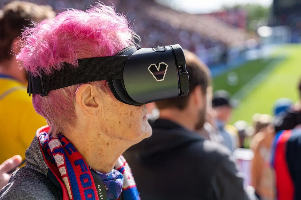 Crystal Palace fan with short pink hair watches a game through a GetVision headset