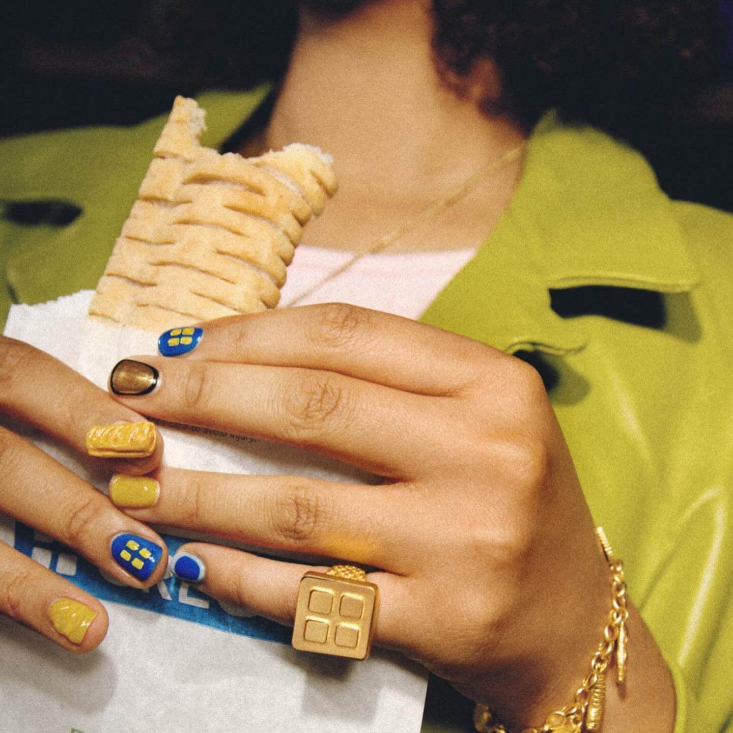 Adorned with Baked in Gold jewelry, hands holding a Greggs sausage roll