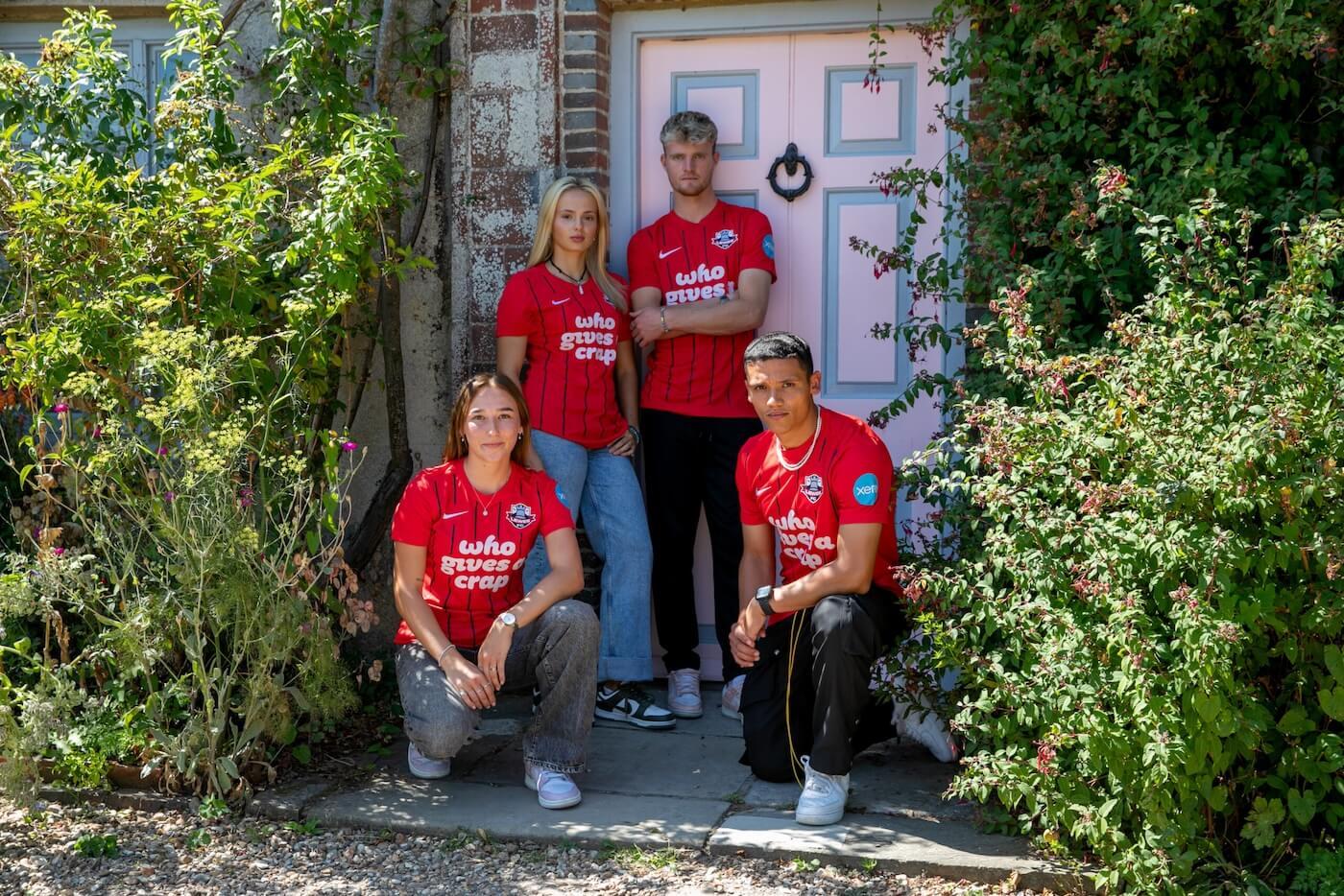 Male and female Lewes FC players in their new team shirts, featuring the text 'Who Gives A Crap'