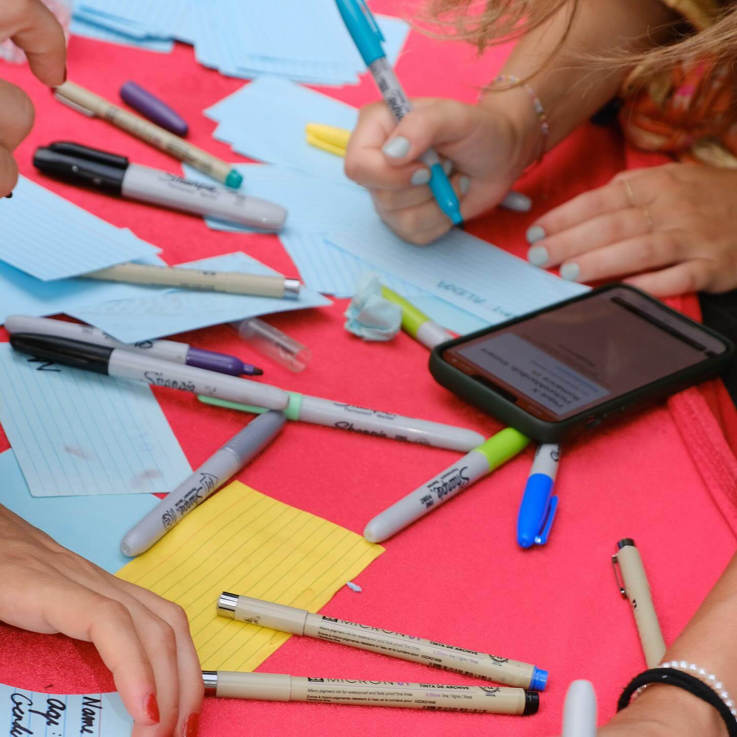 Pens, index cards and hands using both