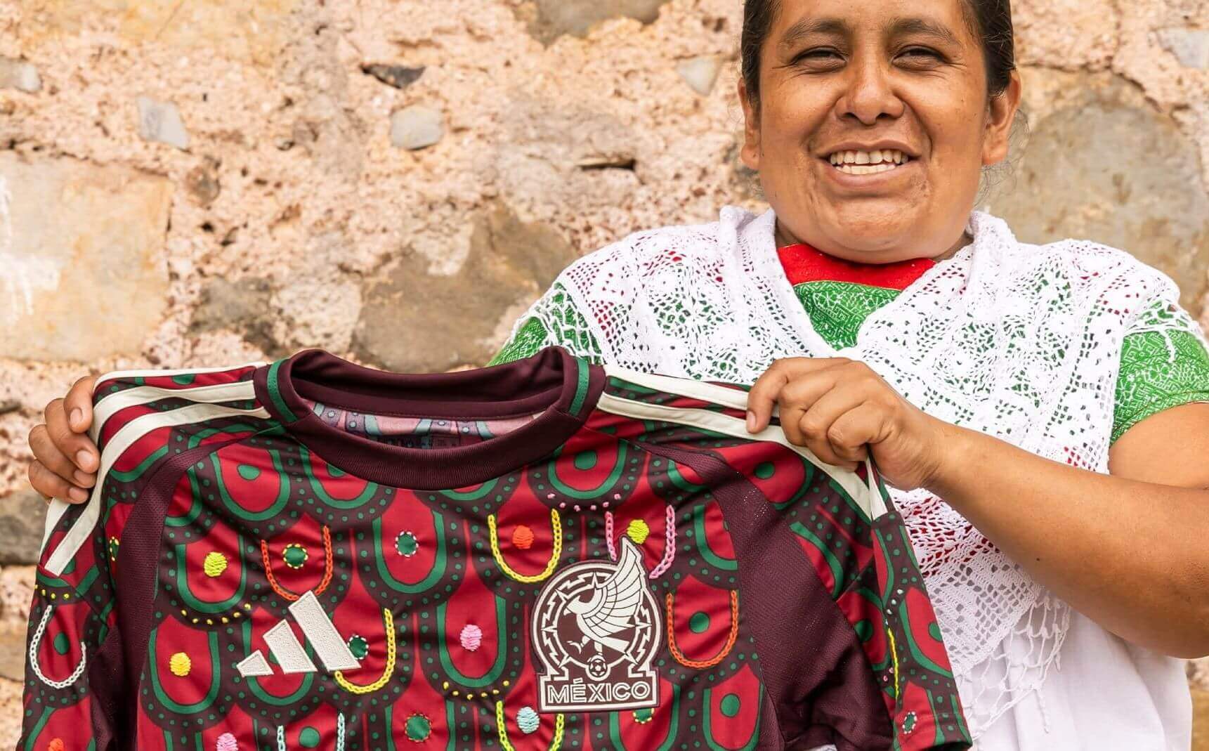 Mexican maker holding a national soccer jersey she embroidered 