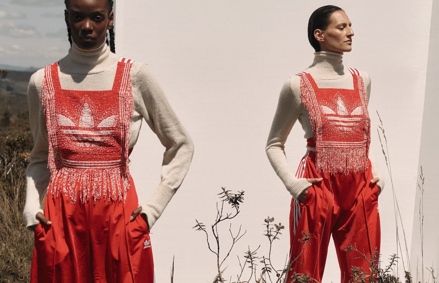 Three women wearing red Adidas tracksuits with white fringes and a large trefoil logo 