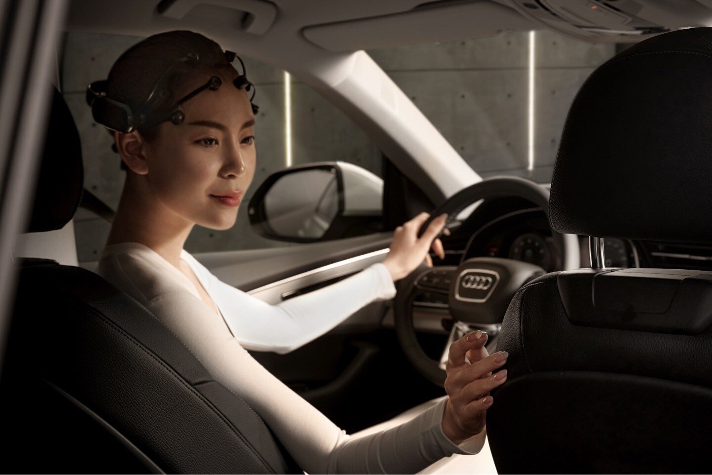 Woman behind the steering wheel of an Audi Q8 2024, wearing an EEG headset 