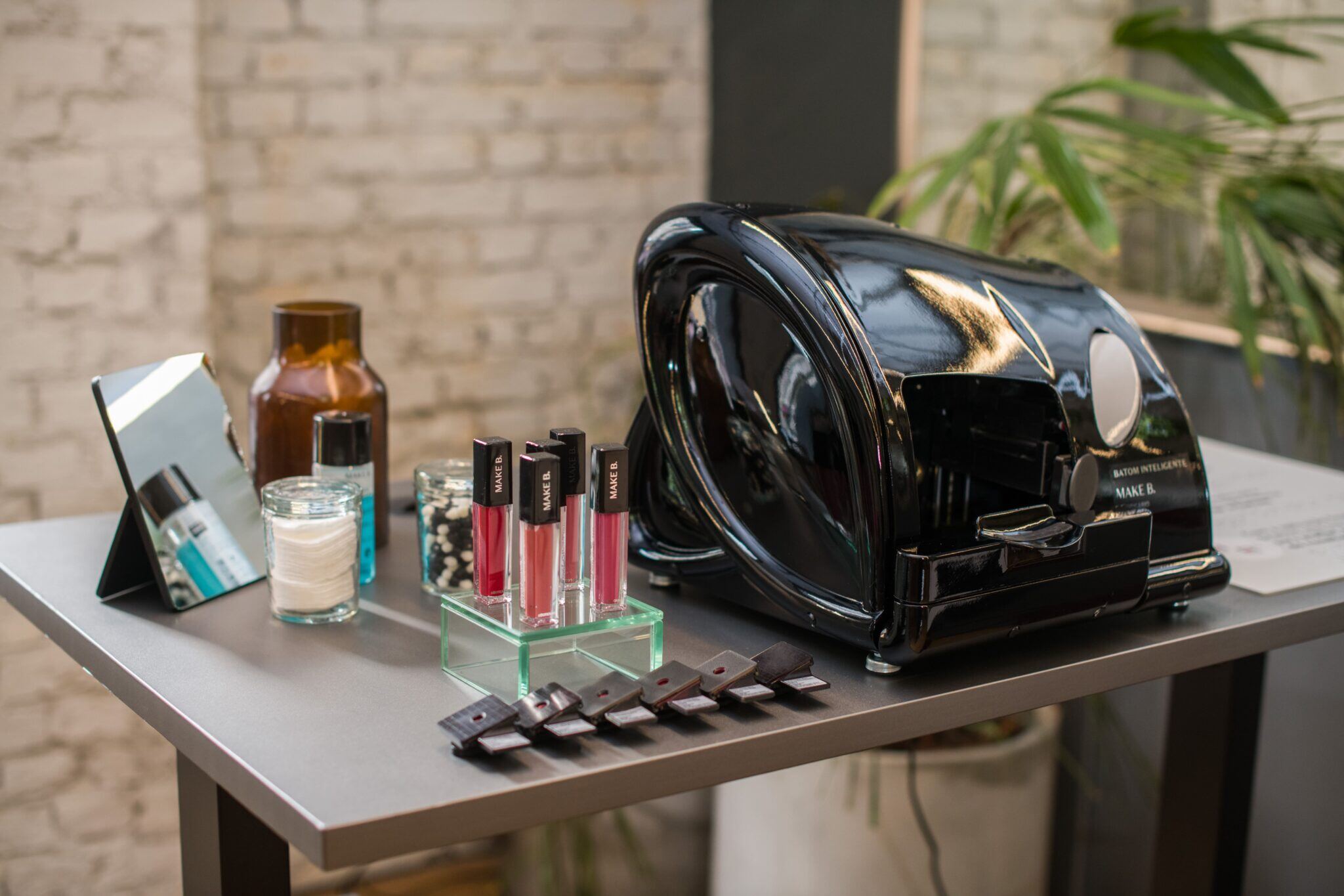 On a table, Boticário’s glossy black Smart Lipstick device, along with various beauty products 