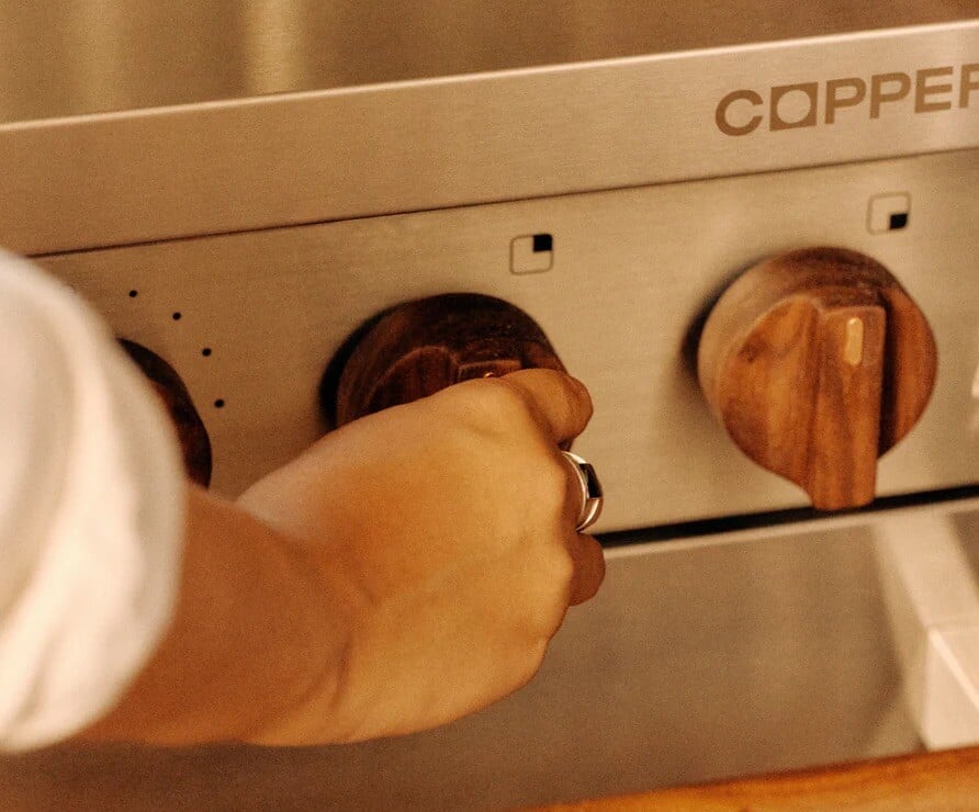 Hand turning a wooden dial on a Charlie stove by Copper 