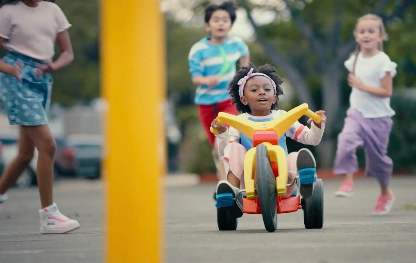 Young girl pedaling hard on a Big Wheel tricycle 