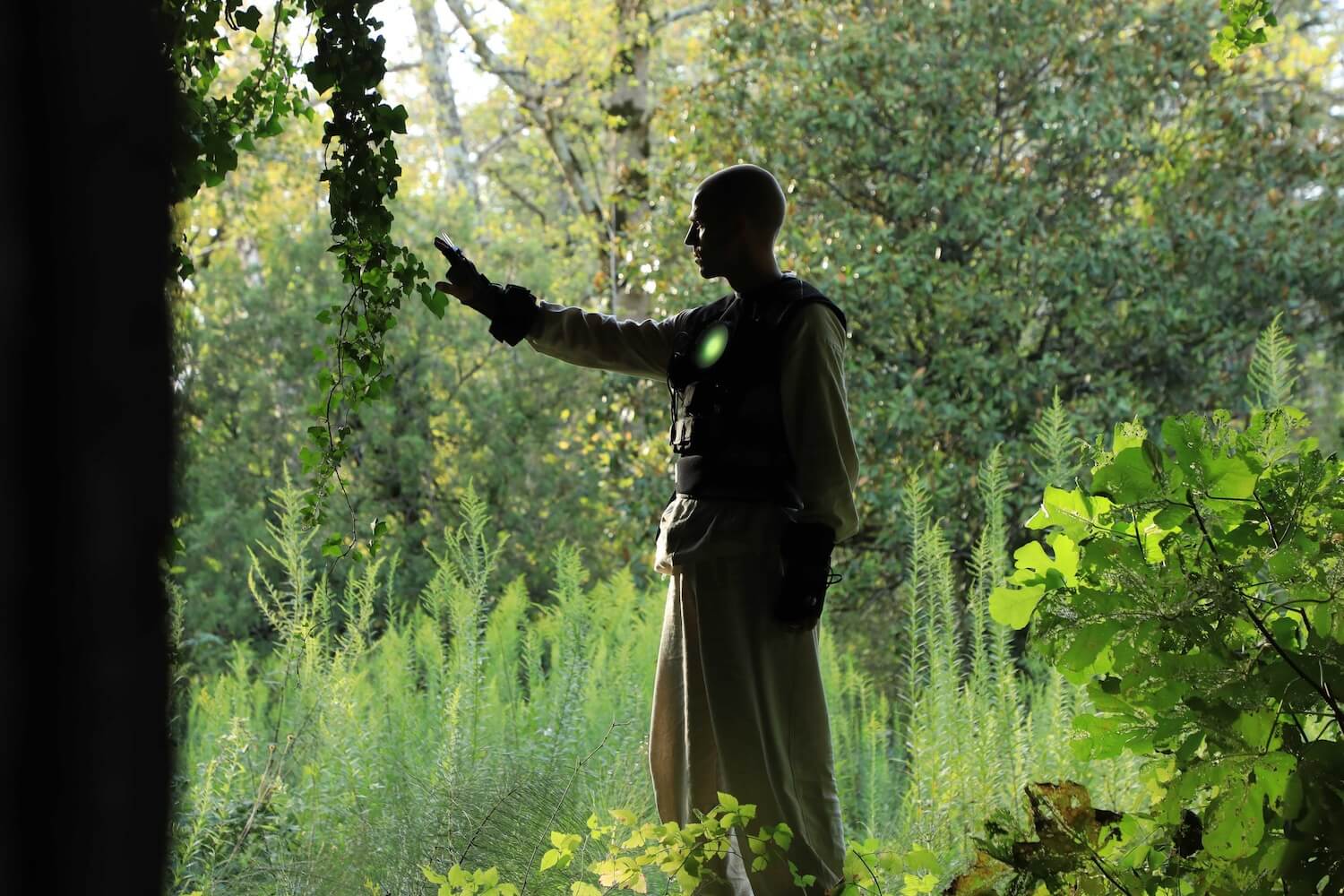 Person in natural surroundings wearing a vest and glove that pick up environmental signals 