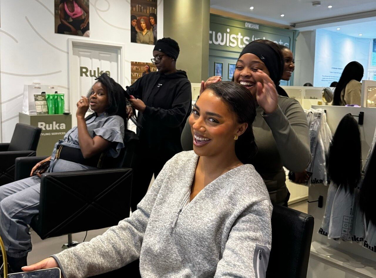 Woman smiling at the viewer as her hair is styled in a salon 