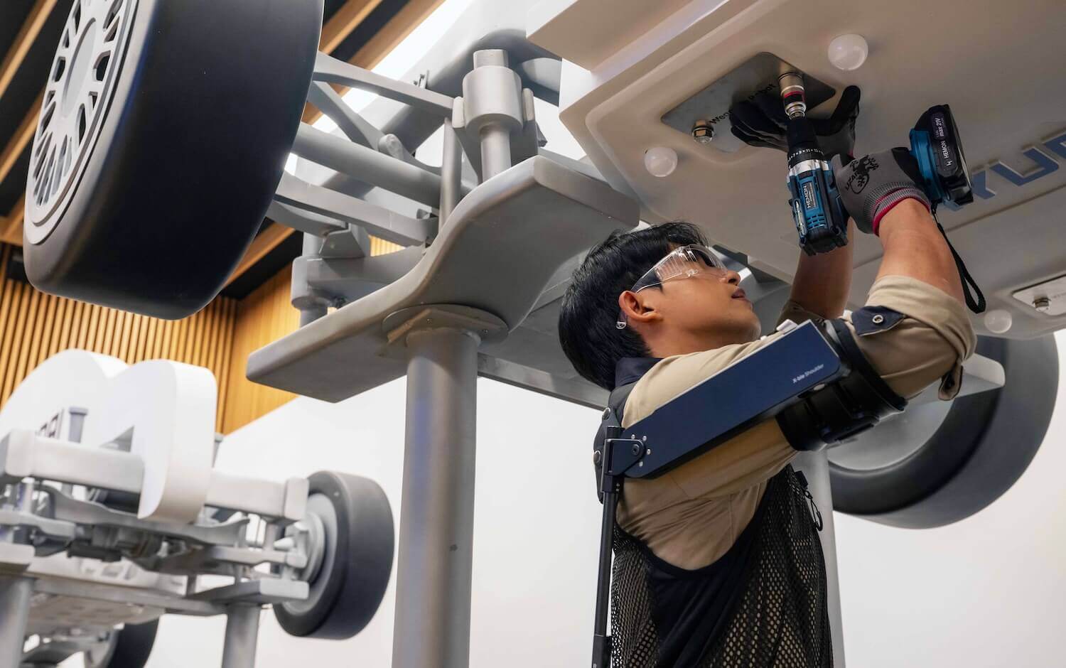 Automotive worker tightening a bolt on an overhead vehicle  