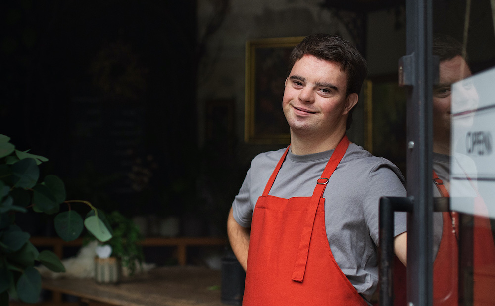 Man in red apron holding a door open