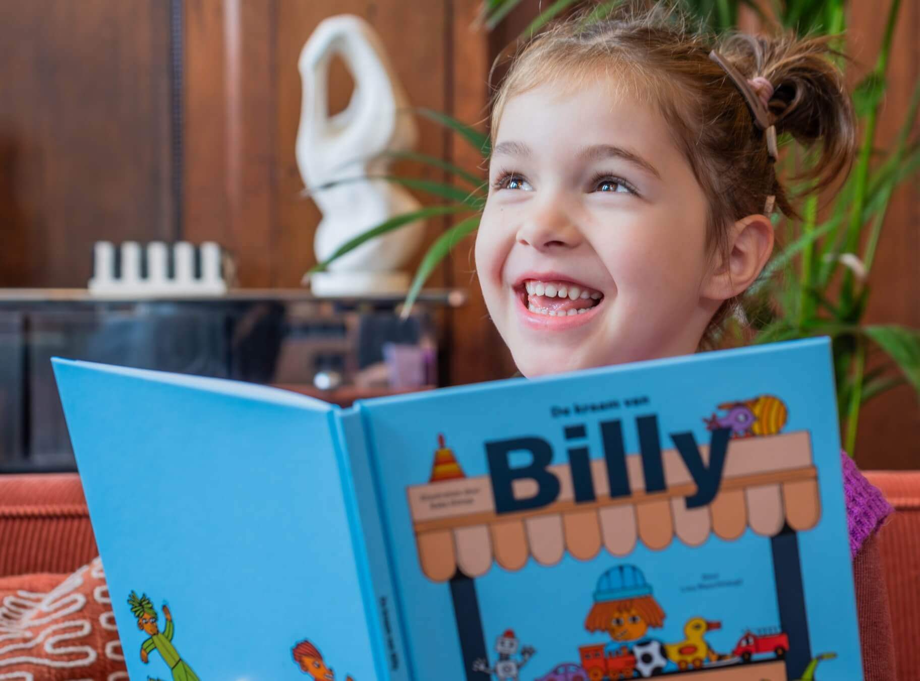 Happy-looking child reading 'De kraam van Billy' 