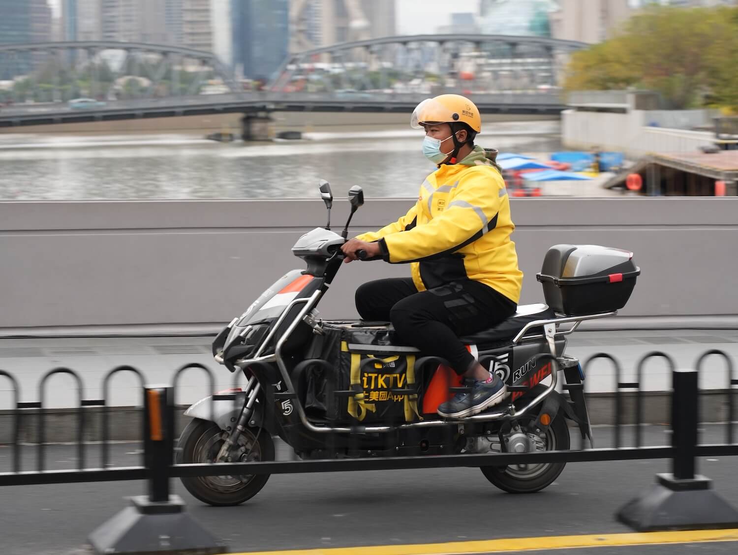 Delivery driver on a moped, wearing a yellow Meituan uniform 