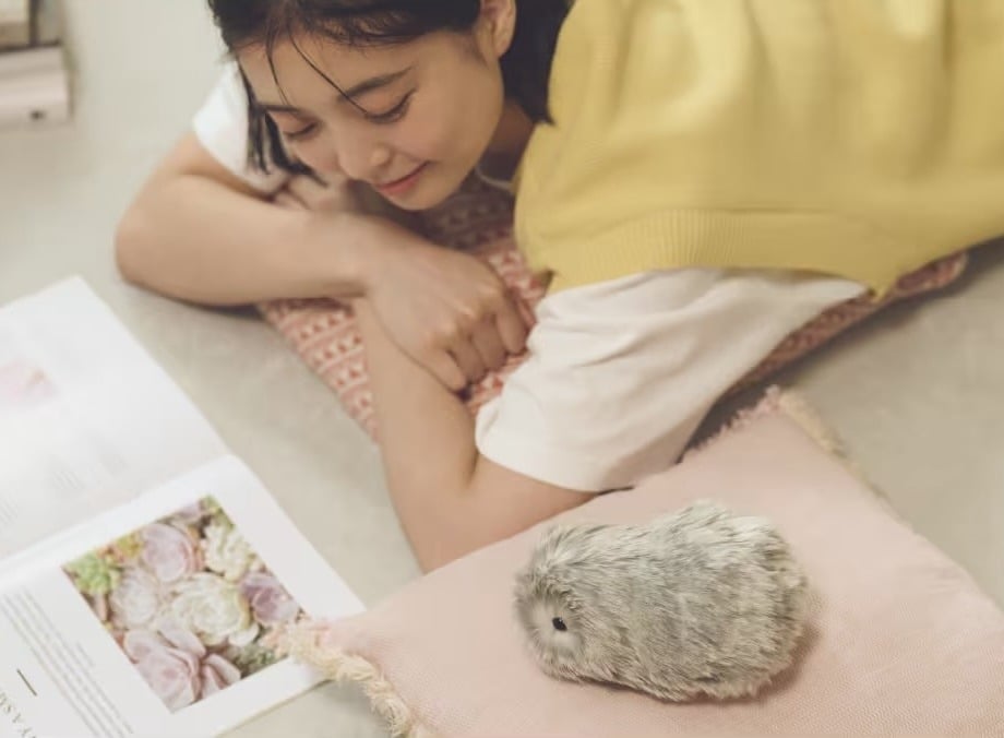 Lying on the floor reading, a girl and her fluffy little Moflin