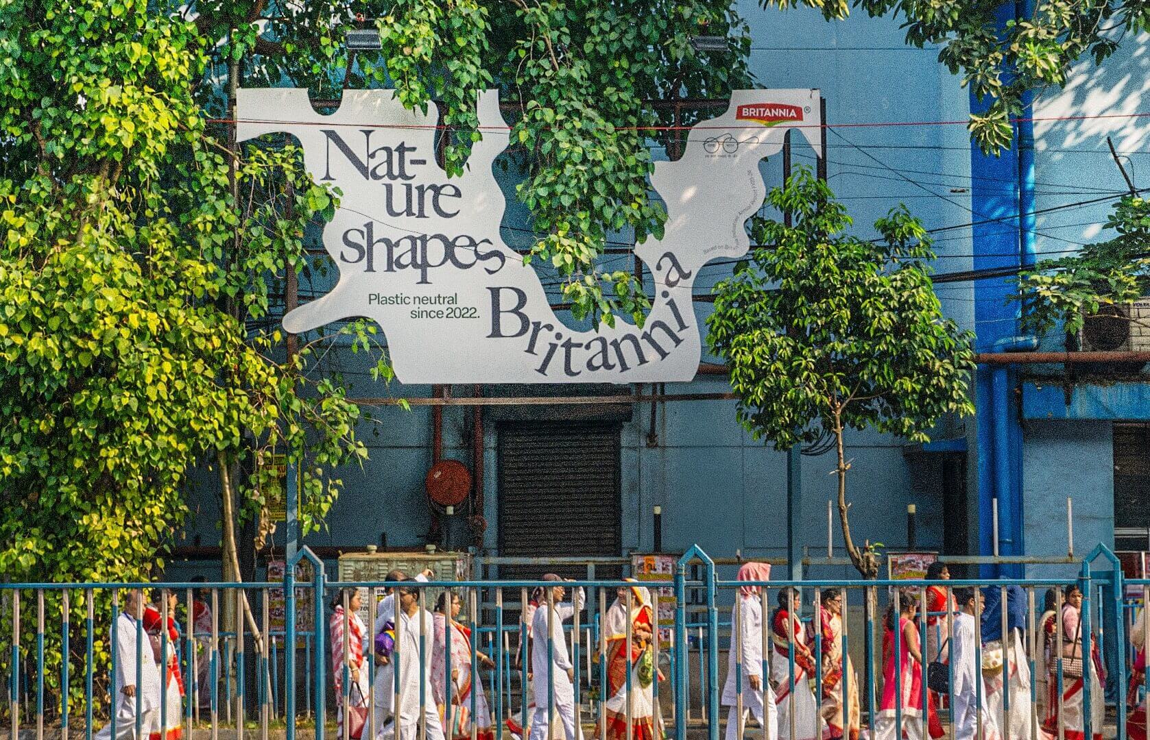 A billboard in an urban environment, shaped to fit around surrounding tree branches 