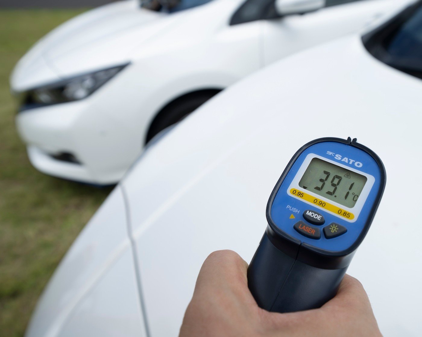 Temperature (39.1°C) being measured of the exterior of a white car 