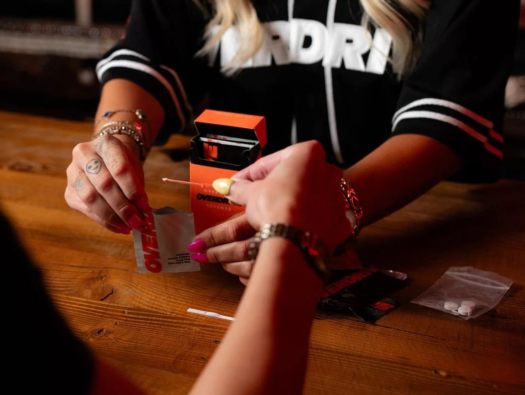 Two people with brightly-colored nail polish using an Overdrive testing kit 