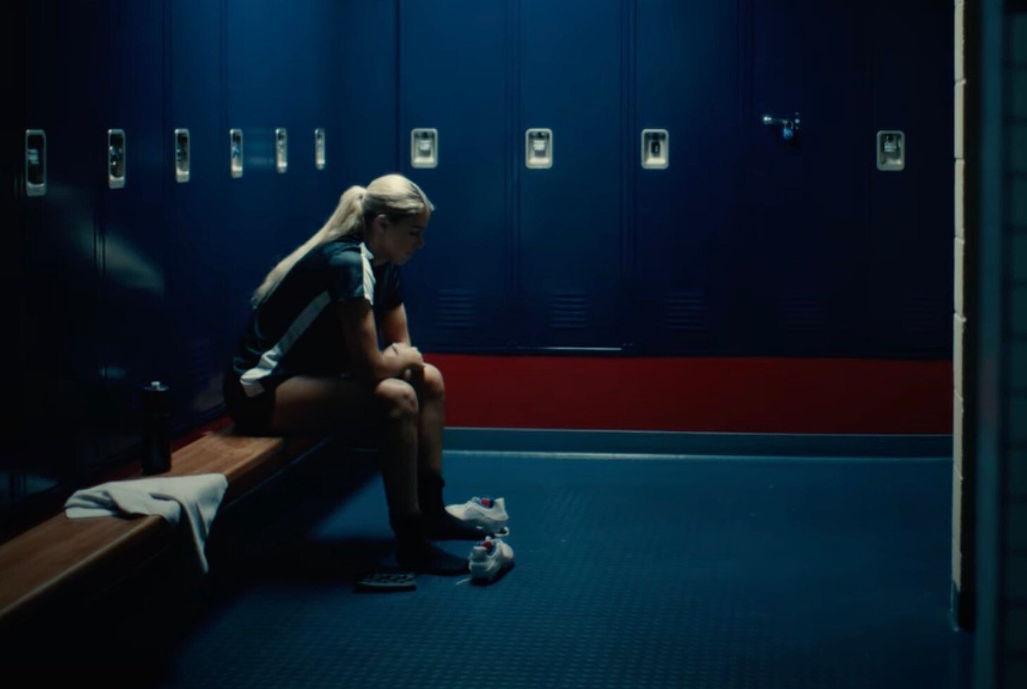 Athlete seated in a dark locker room, looking down 