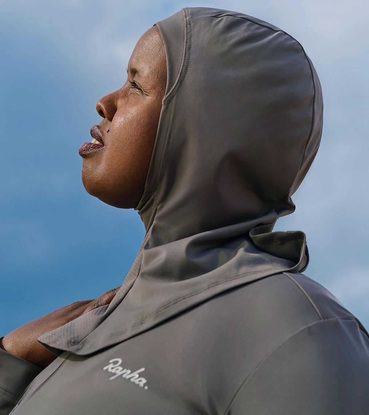 Female cyclist wearing a Rapha hijab, looking up at the sky 