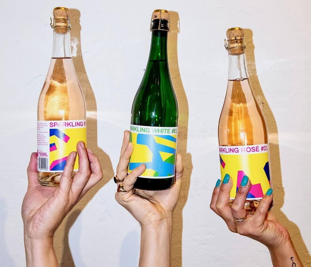 Three hands holding up three bottles of Rotterdam Urban Winery's wine 