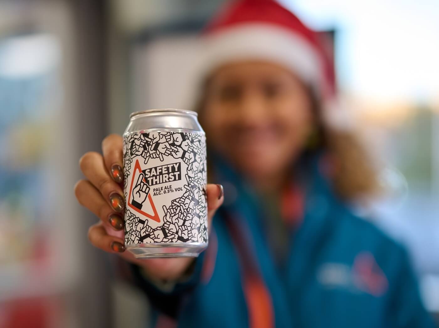 Railway worker in a Santa hat holding a can of Safety Thirst beer  