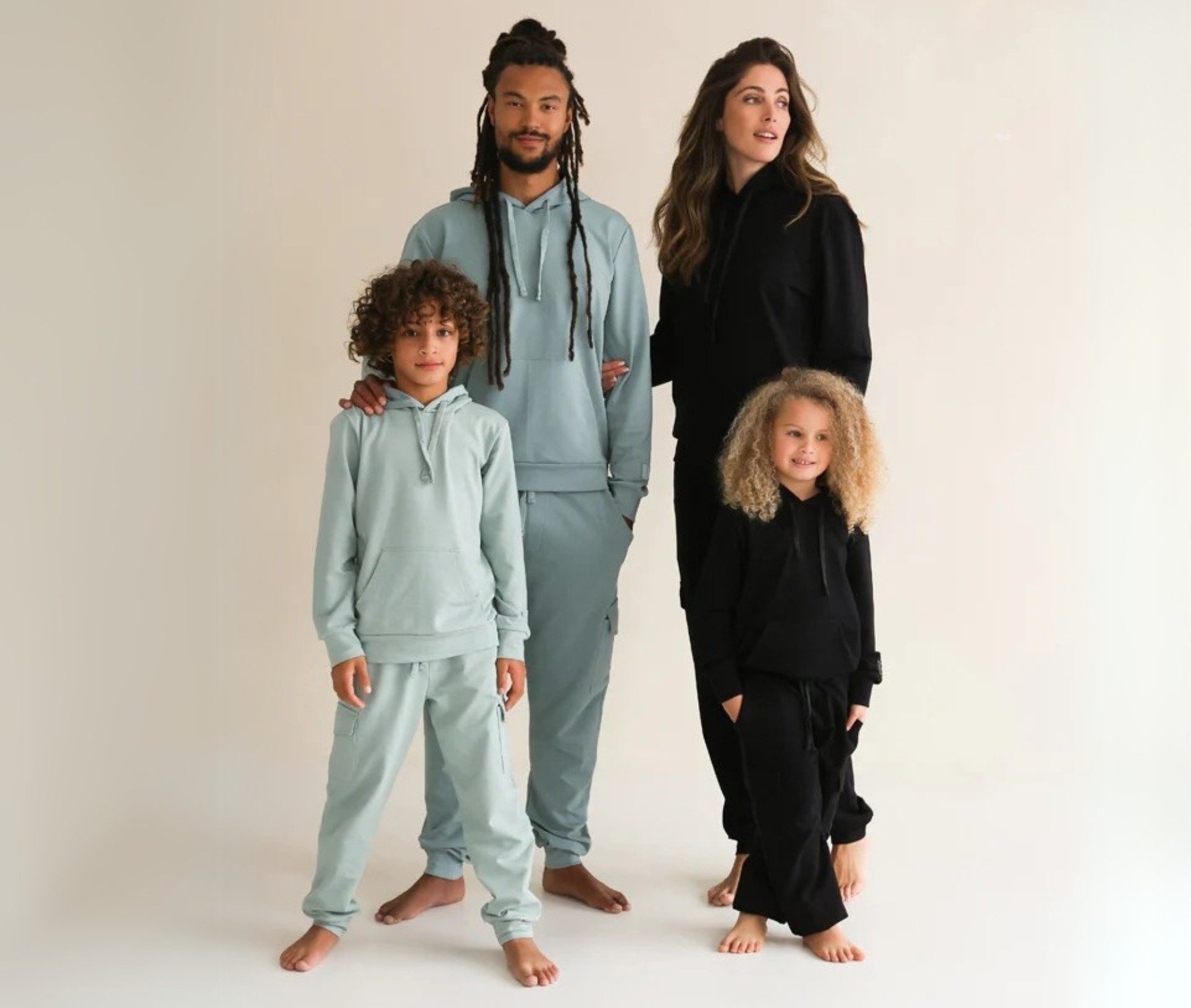 Two adults and two children wearing Shami Family tracksuits in light teal and black 