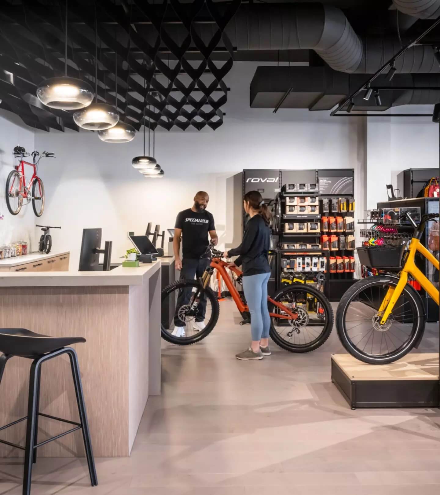 Person next to a bike, holding the handlebars and talking to a bicycle shop employee 