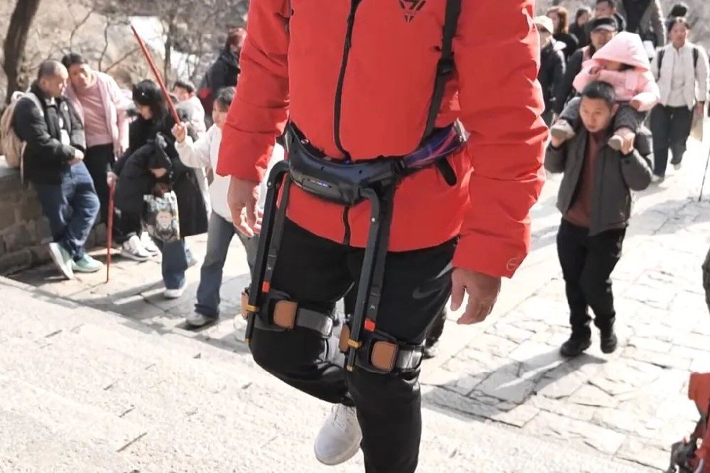 Person climbing steps wearing an exoskeleton around their waist and upper legs 