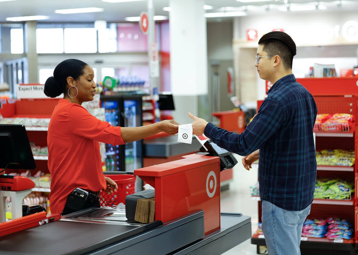 A Target cashier hands a receipt to a customer 