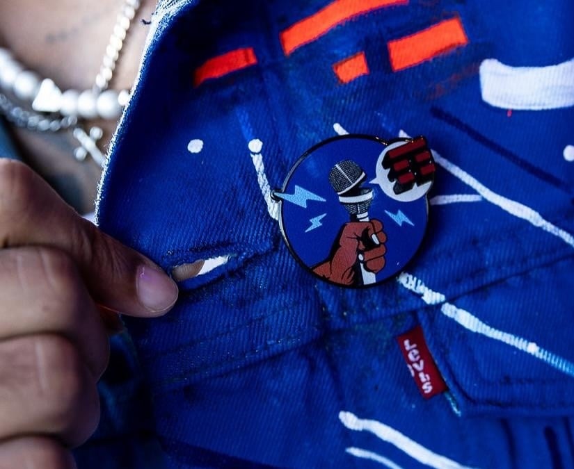 Close-up of a TIM Block Pin on someone's blue jacket 