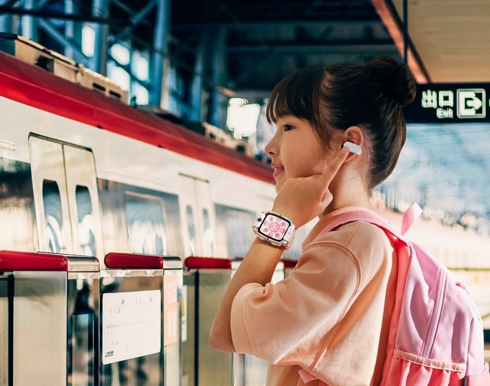 Girl using earphones connected to her smart watch while waiting for a train 