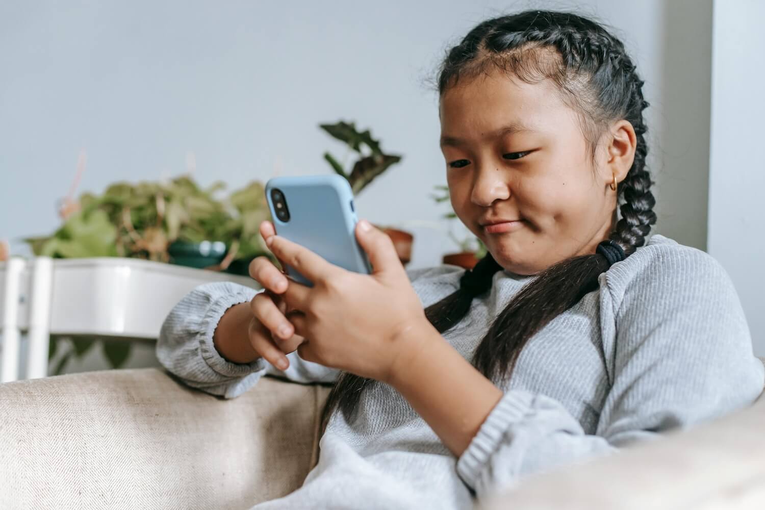 Tween with braids looking at a phone screen 